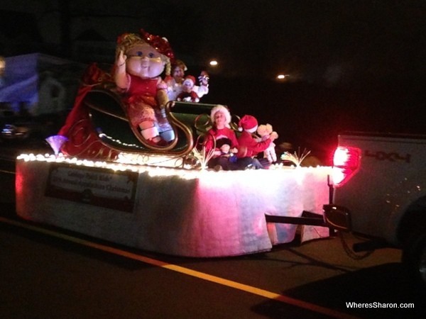 Big cabbage patch kid on a float in christmas parade at night